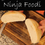 Homemade bread in the Ninja Foodi cut in half on a cutting board