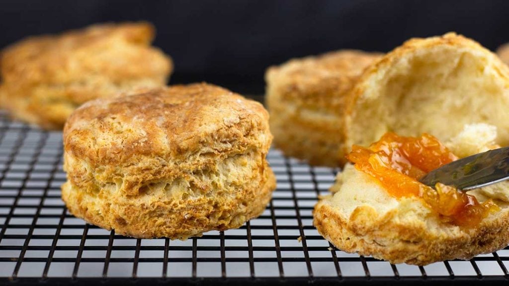 Homemade biscuits on a cooling rack with orange marmalade on one