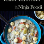 New England Clam Chowder in a blue bowl with oyster crackers and a spoon