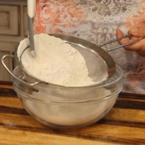 sifting flour into a bowl for Asian Steamed Buns