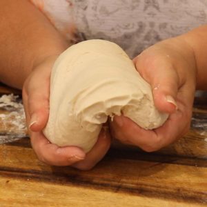 Smooth dough ball being stretched