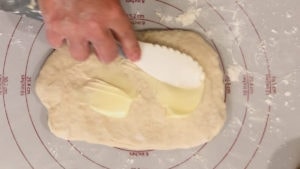 adding butter to deep dish pizza dough