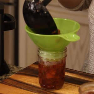 putting strawberry preserves in a jelly jar