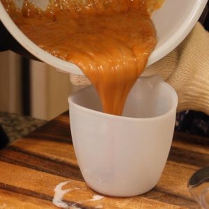 Pouring homemade caramel sauce into silicone measure cup