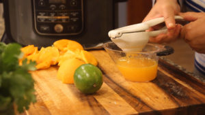 using a citrus press to squeeze orange juice for carne asada marinade
