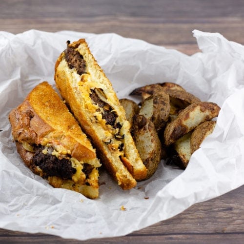 Patty Melt cut with fries on parchment