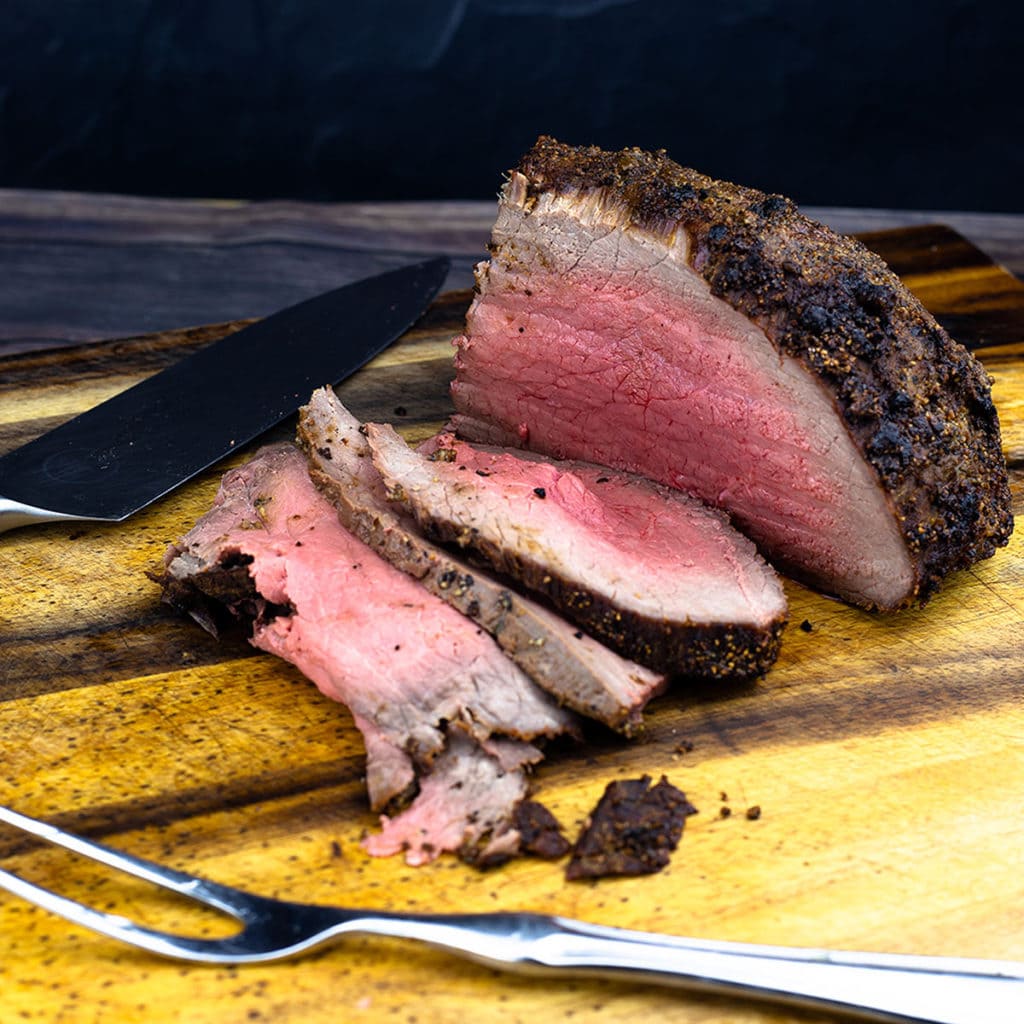 Roast Beef medium rare on cutting board being sliced thin
