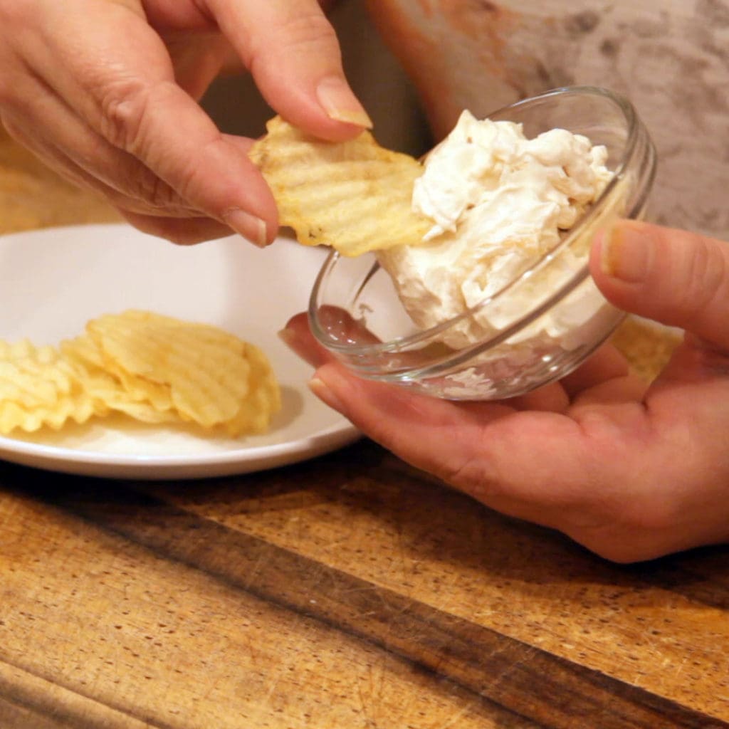 scooping out french onion dip with a chip