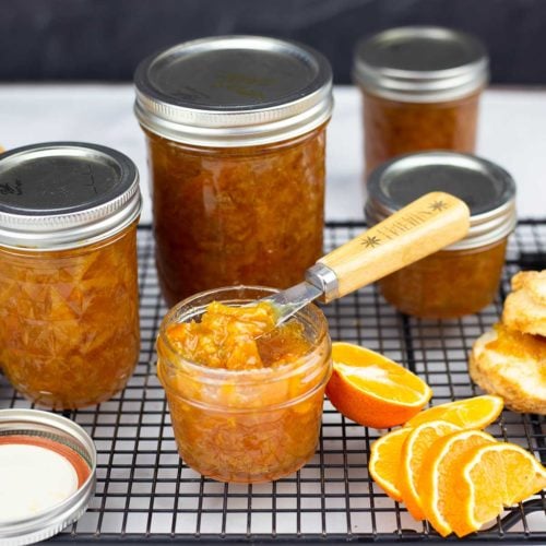 Orange Marmalade in jars with one open and biscuits beside it