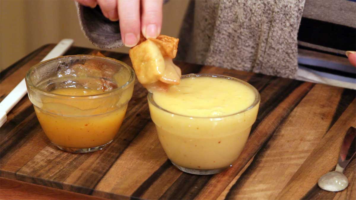 Dipping a crab rangoon into the pineapple sweet and sour sauce