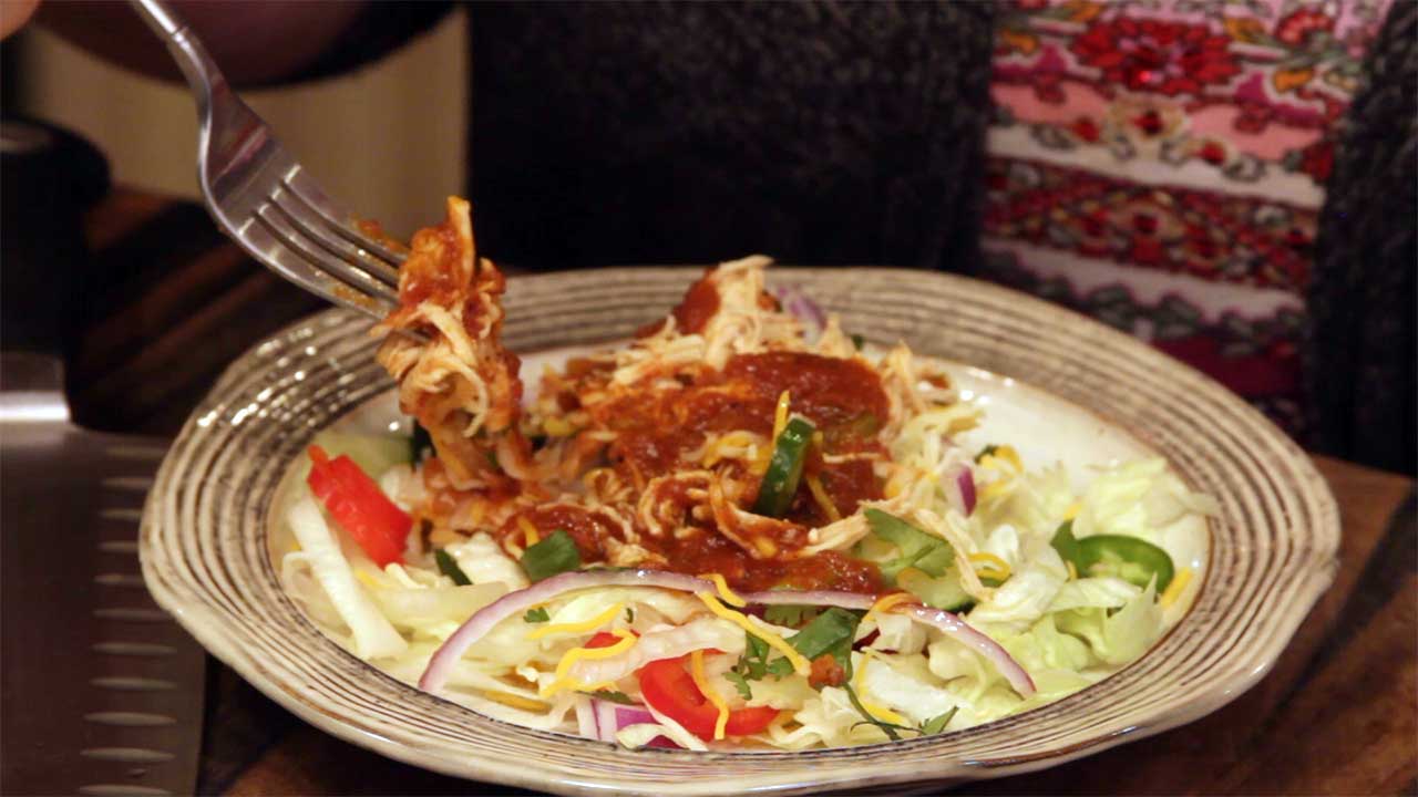 Shredded Mexican Chicken on top of a salad with enchilada sauce as the dressing