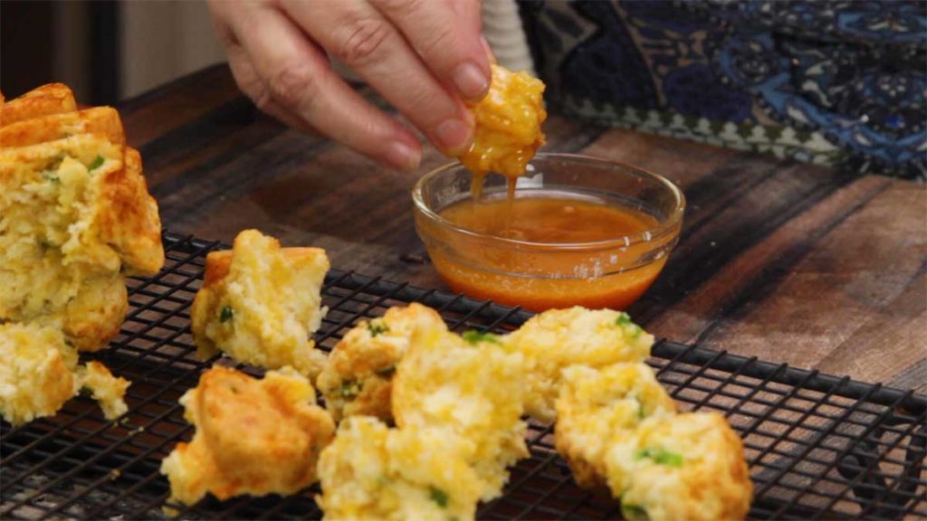 dipping the jalapeno cheddar pull-apart bread into dipping sauce