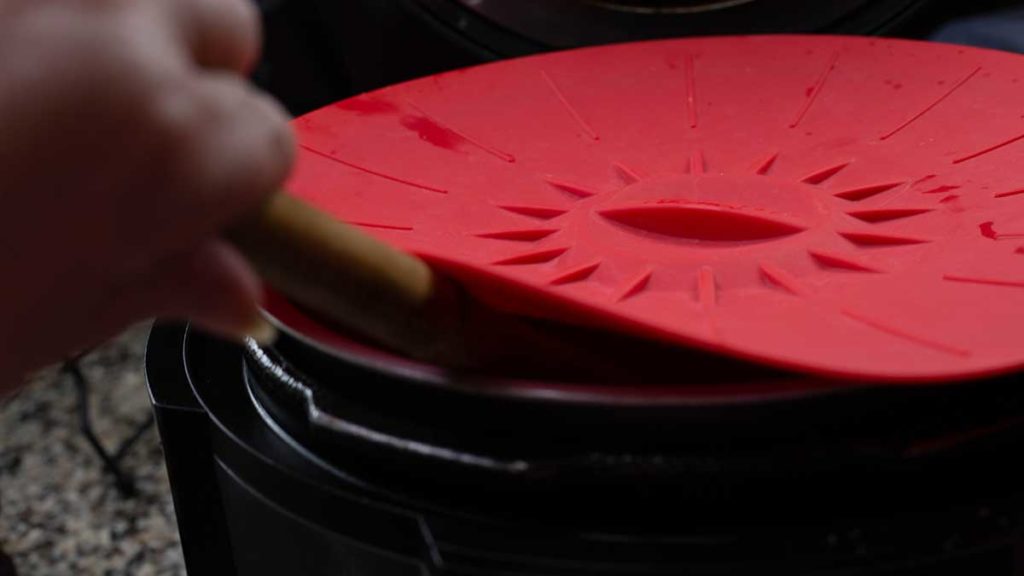red silicone cover over the inner pot of the foodi with a spoon slipping into the pot