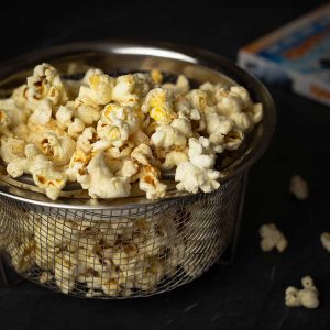 Ninja Foodi Popcorn in a mesh bowl with a DVD jacket behind it