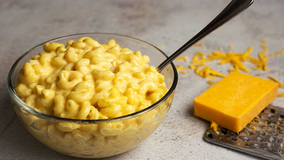 mac and cheese in a bowl with a block of cheese beside it
