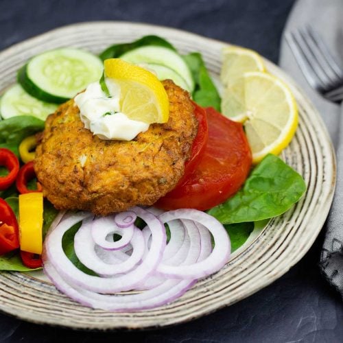 Salmon Patty on a salad with a bit of tarragon mayo and a lemon wedge