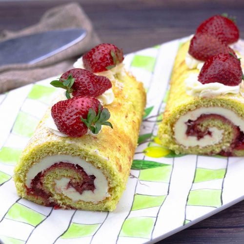 Strawberry roll cake cut in half on a platter