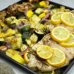 lemon rosemary chicken with potatoes and veggies on the sheet pan after being cooked.