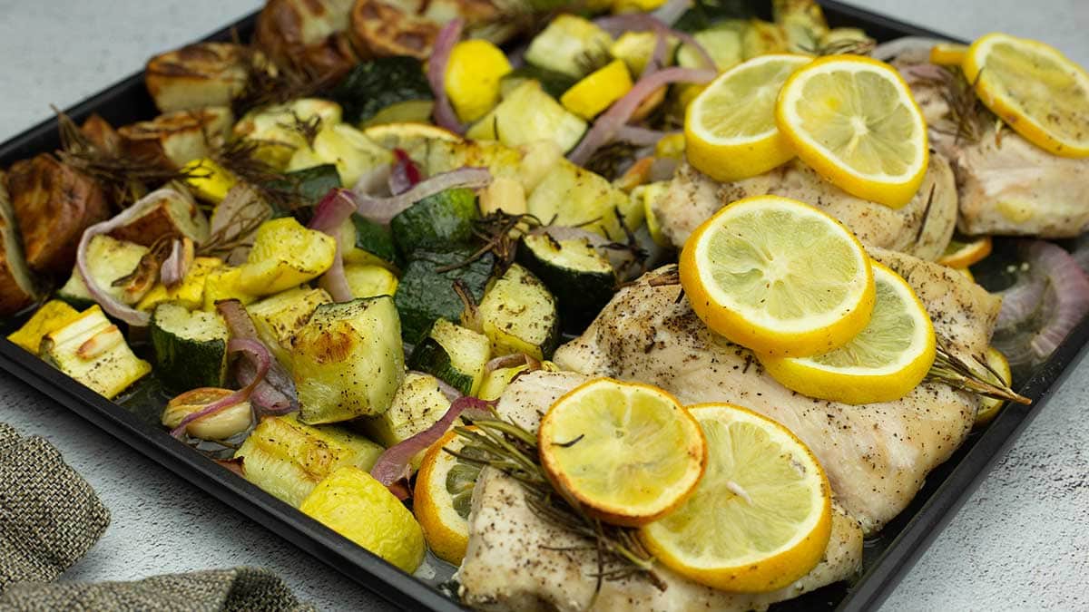lemon rosemary chicken with potatoes and veggies on the sheet pan after being cooked.