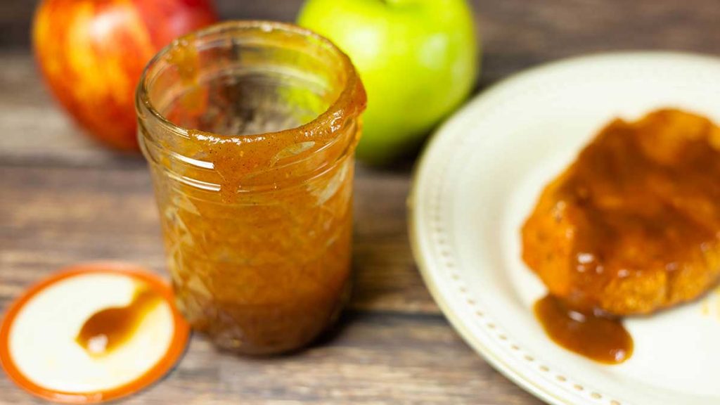 apple butter bourbon bbq sauce in a jar with a pork chop covered in bbq sauce