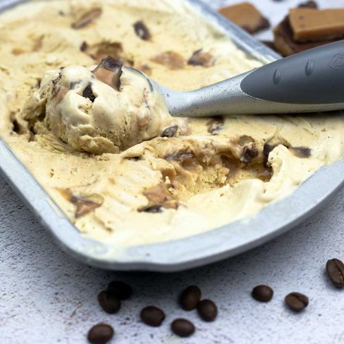 coffee toffee ice cream in a metal container with an ice cream scoop of ice cream