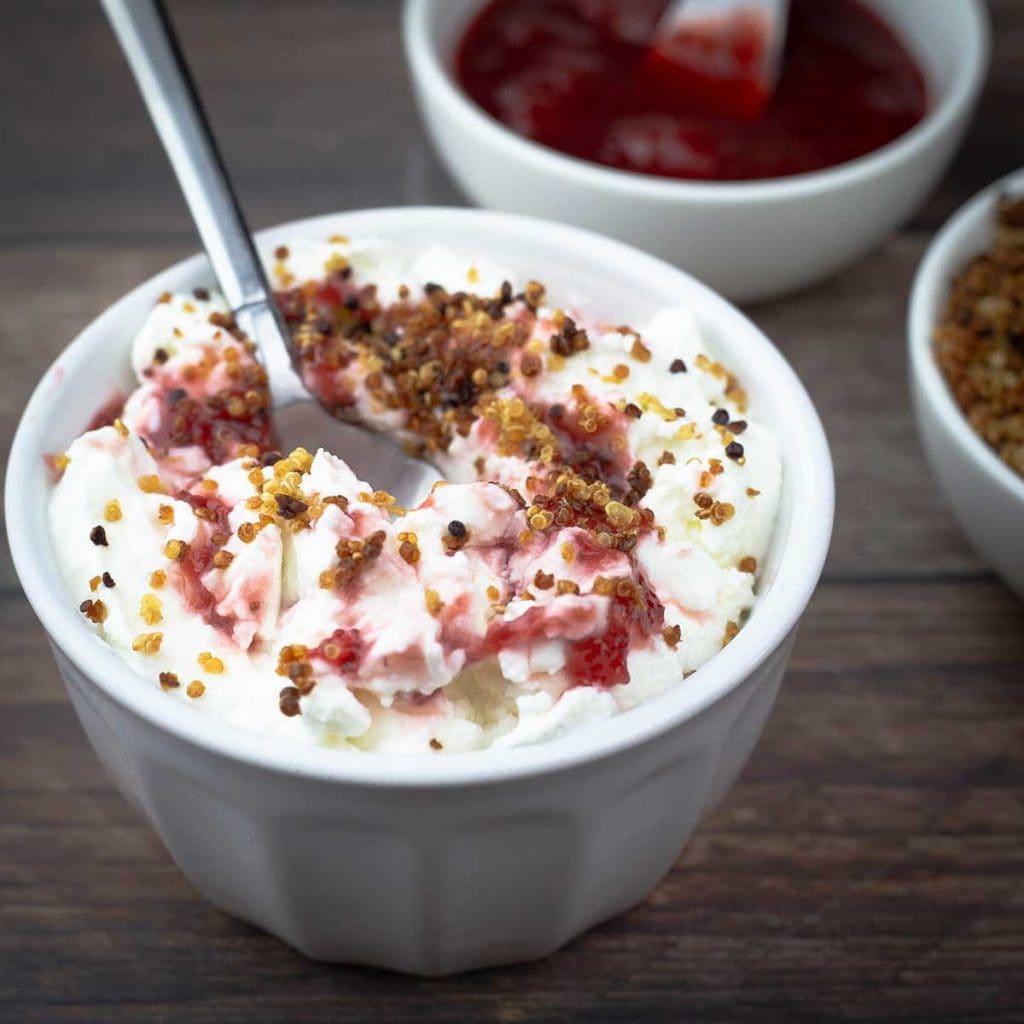 cold start yogurt in a bowl with strawberry preserves and quinoa crumble