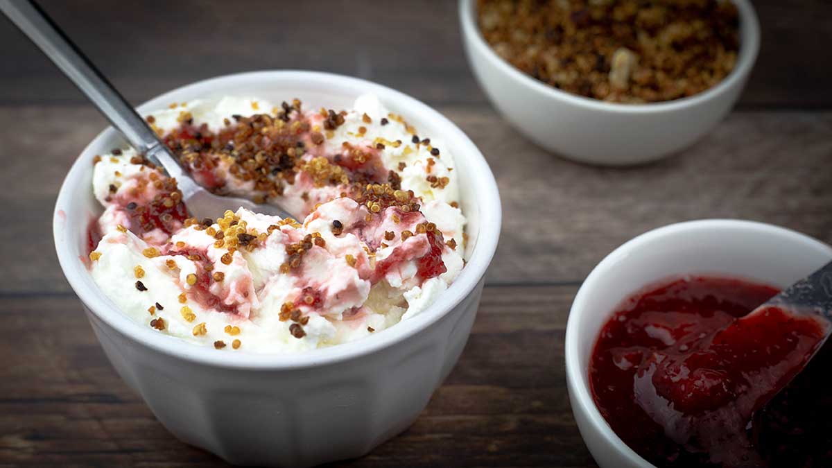 cold start yogurt in a bowl with strawberry preserves and quinoa crumble