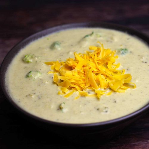 bowl of broccoli and cheese soup with shredded cheddar on top