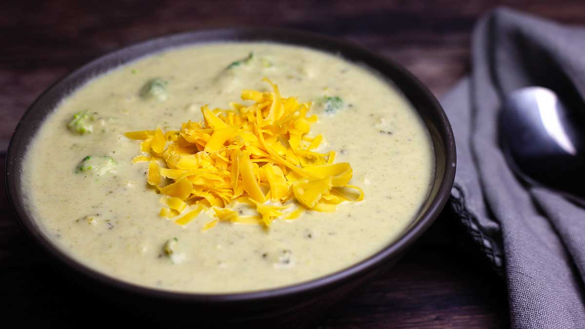 bowl of broccoli and cheese soup with shredded cheddar on top