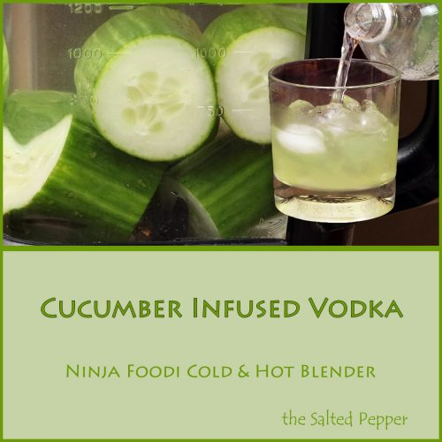 cucumber infused vodka in a glass with cucumbers in the blender behind it