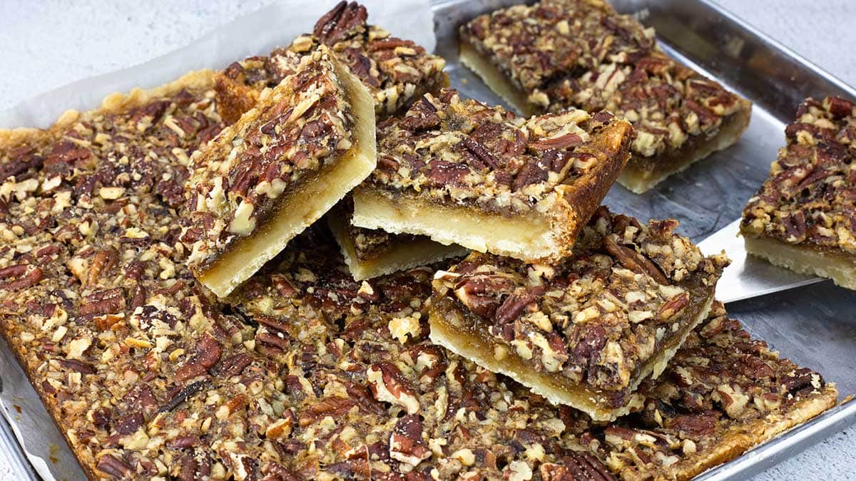 pecan bars cut and piled up on a sheet pan