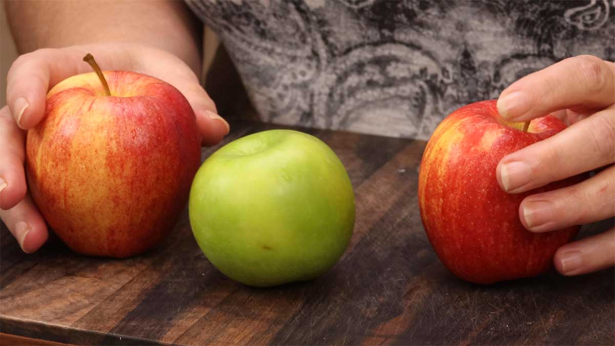 three varieties of apples on a cutting board