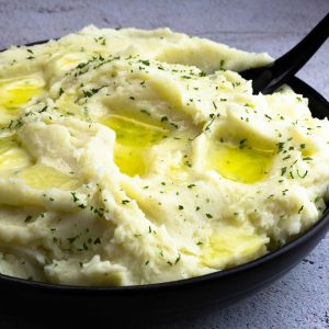 creamy mashed potatoes with butter in a black serving bowl