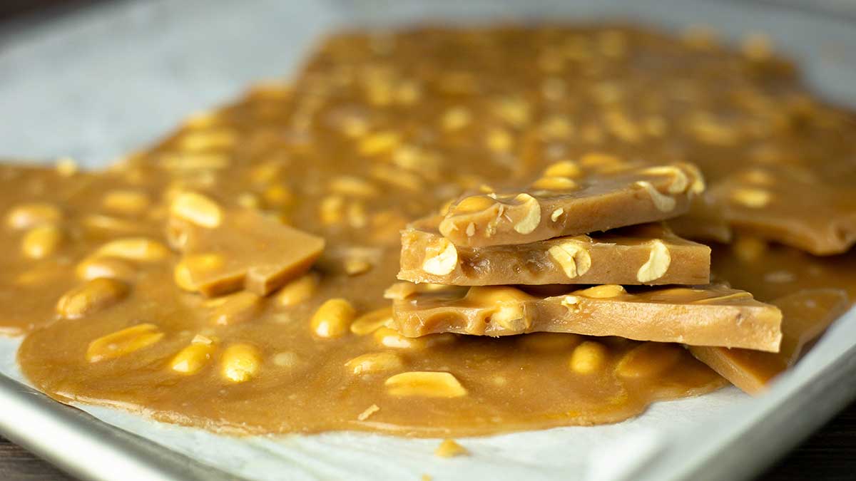 peanut brittle on a tray with pieces stacked on top