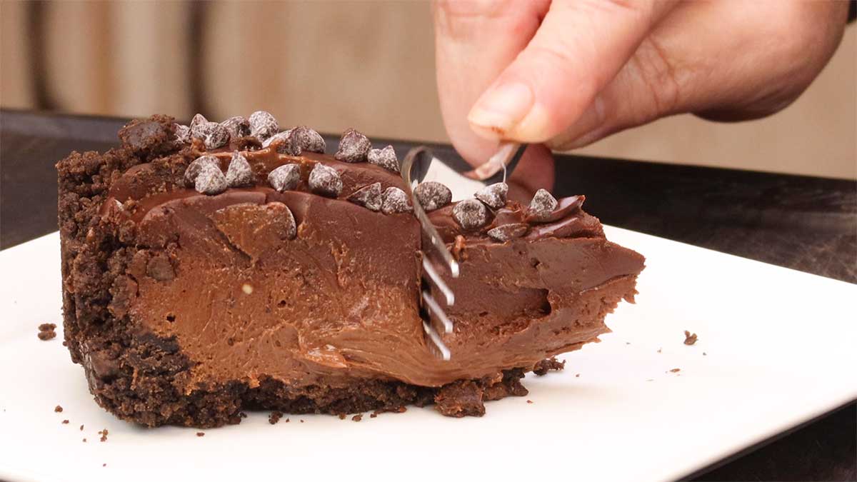 cutting into a slice of triple chocolate cheesecake