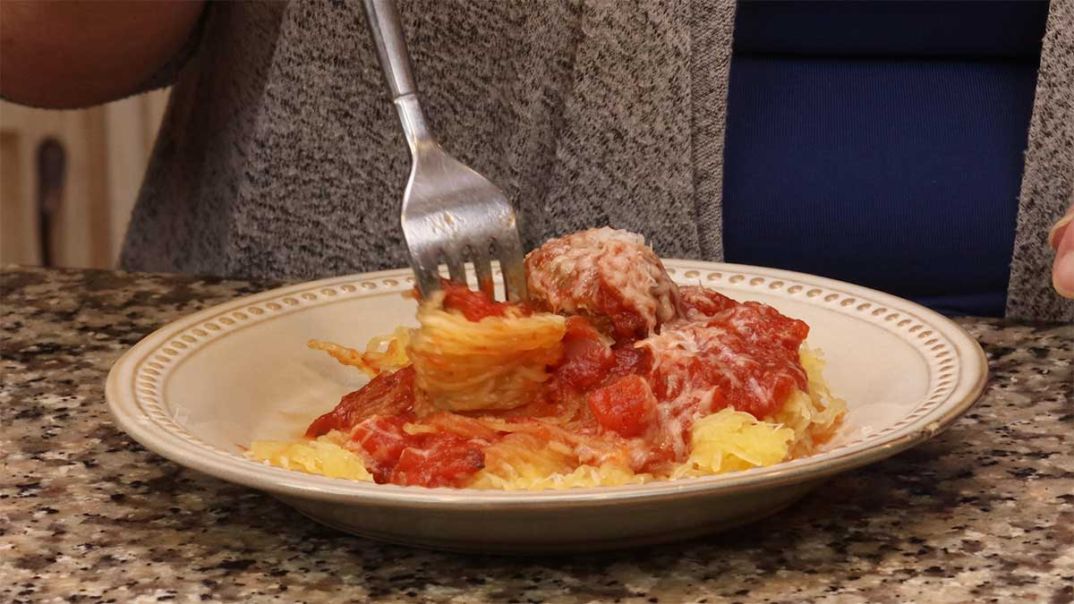 twirling spaghetti squash on a fork with a spaghetti sauce