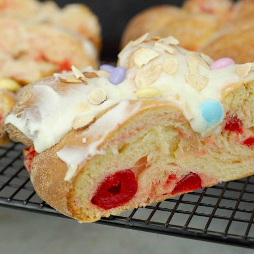 cherry brioche bread with almond glaze cut and on a cooling rack