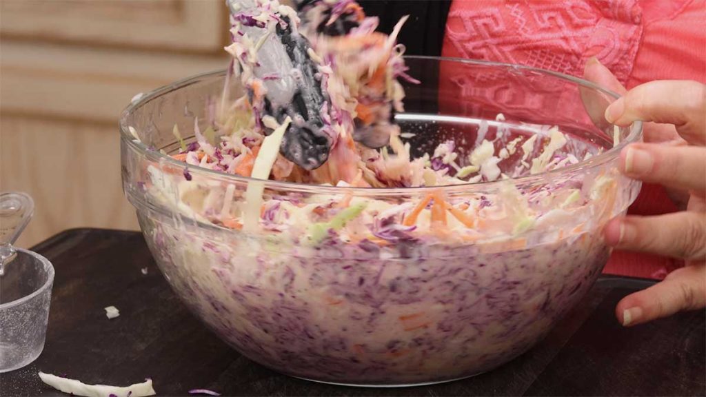 tossing the coleslaw dressing with the coleslaw mix