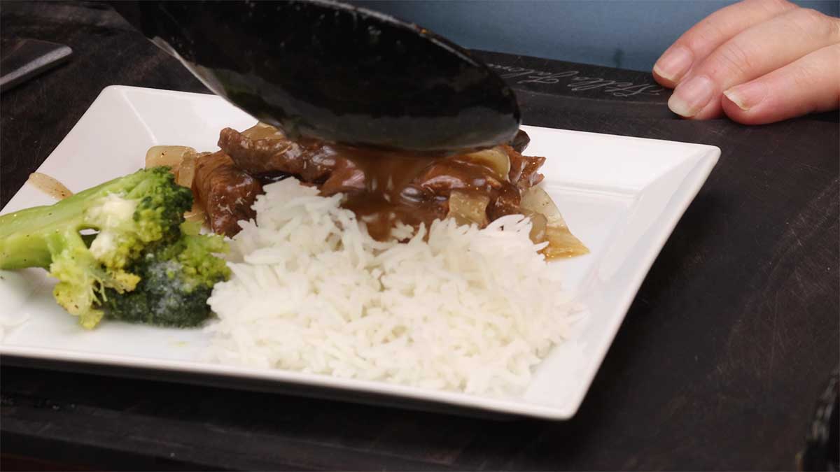 serving beef tips and gravy over rice