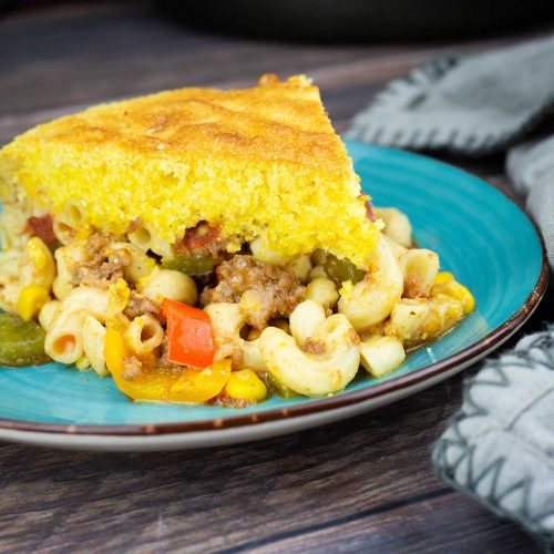southwestern goulash with cornbread topping on a blue plate