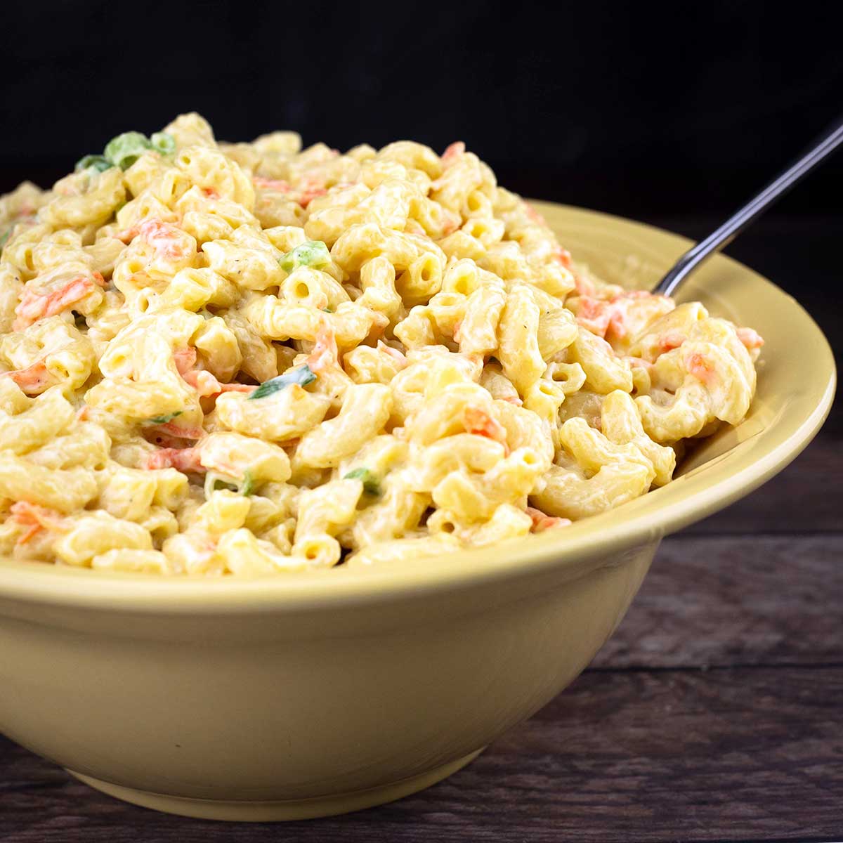 Hawaiian macaroni salad in a yellow bowl with a serving spoon