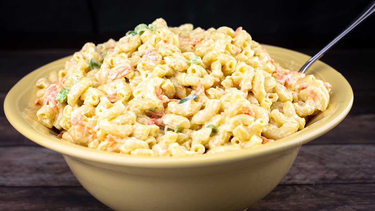 Hawaiian macaroni salad in a yellow bowl with a serving spoon