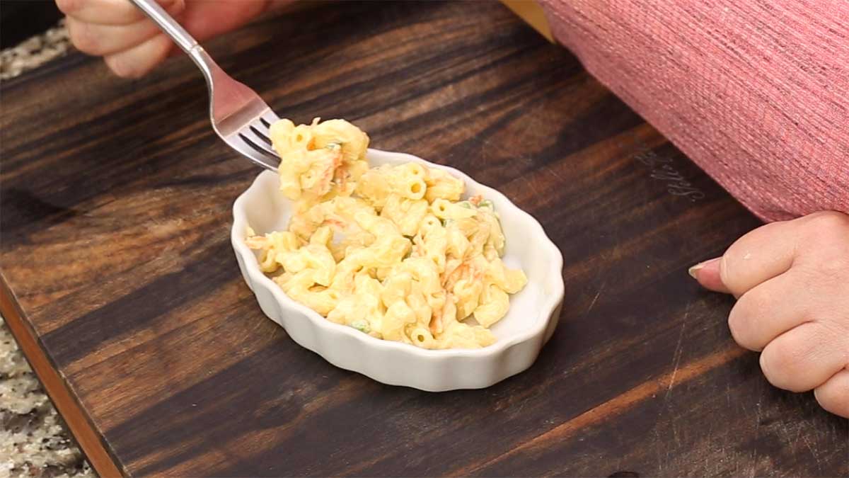 Hawaiian macaroni salad in a small white dish with a forkful being taken out
