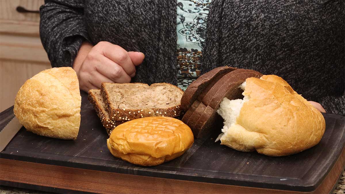 different types of bread and rolls on a wood cutting board