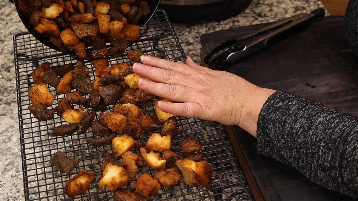 dumping homemade croutons onto a cooling rack