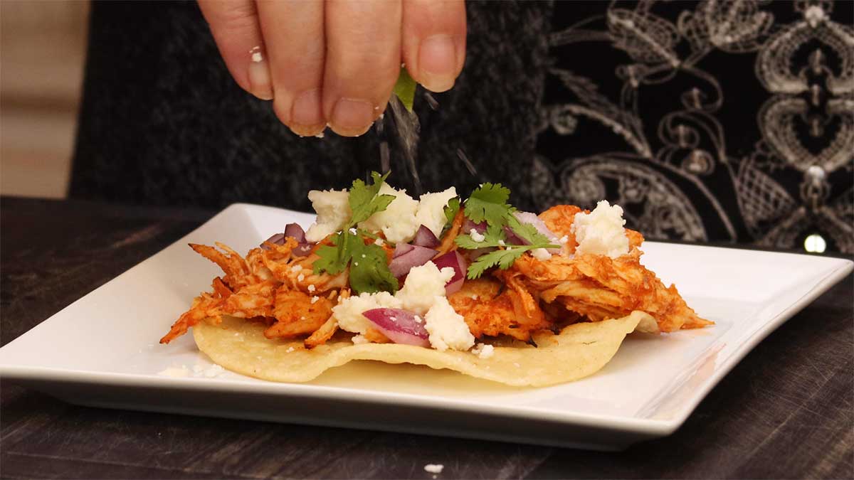 squirting lime on a chicken tinga taco