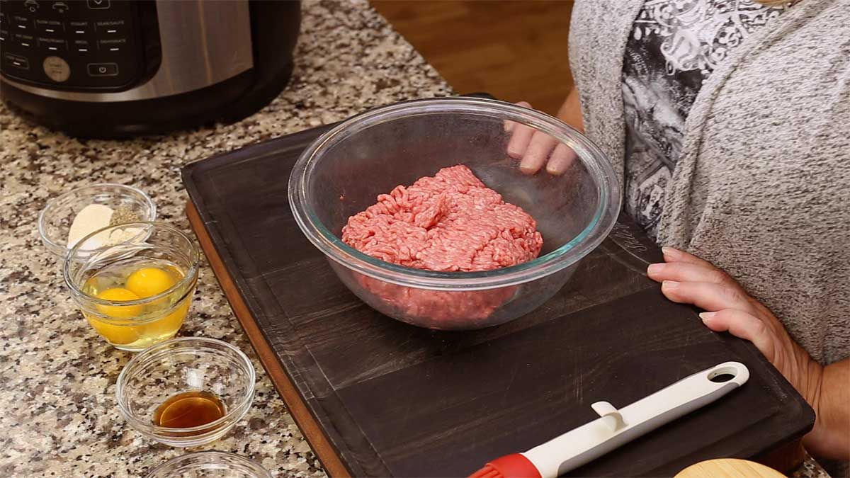 ground beef in a mixing bowl and other ingredients in small balls before mixing
