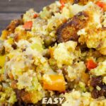 sausage and cornbread stuffing in a white serving bowl with spoon