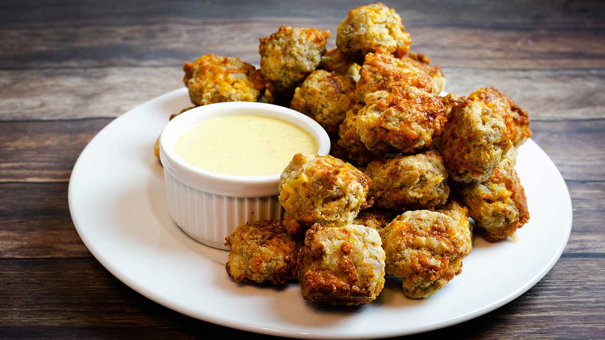 air fryer sausage balls on a white plate with honey mustard dipping sauce