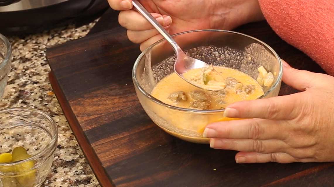 taking a spoonful of cheeseburger soup in a glass bowl 